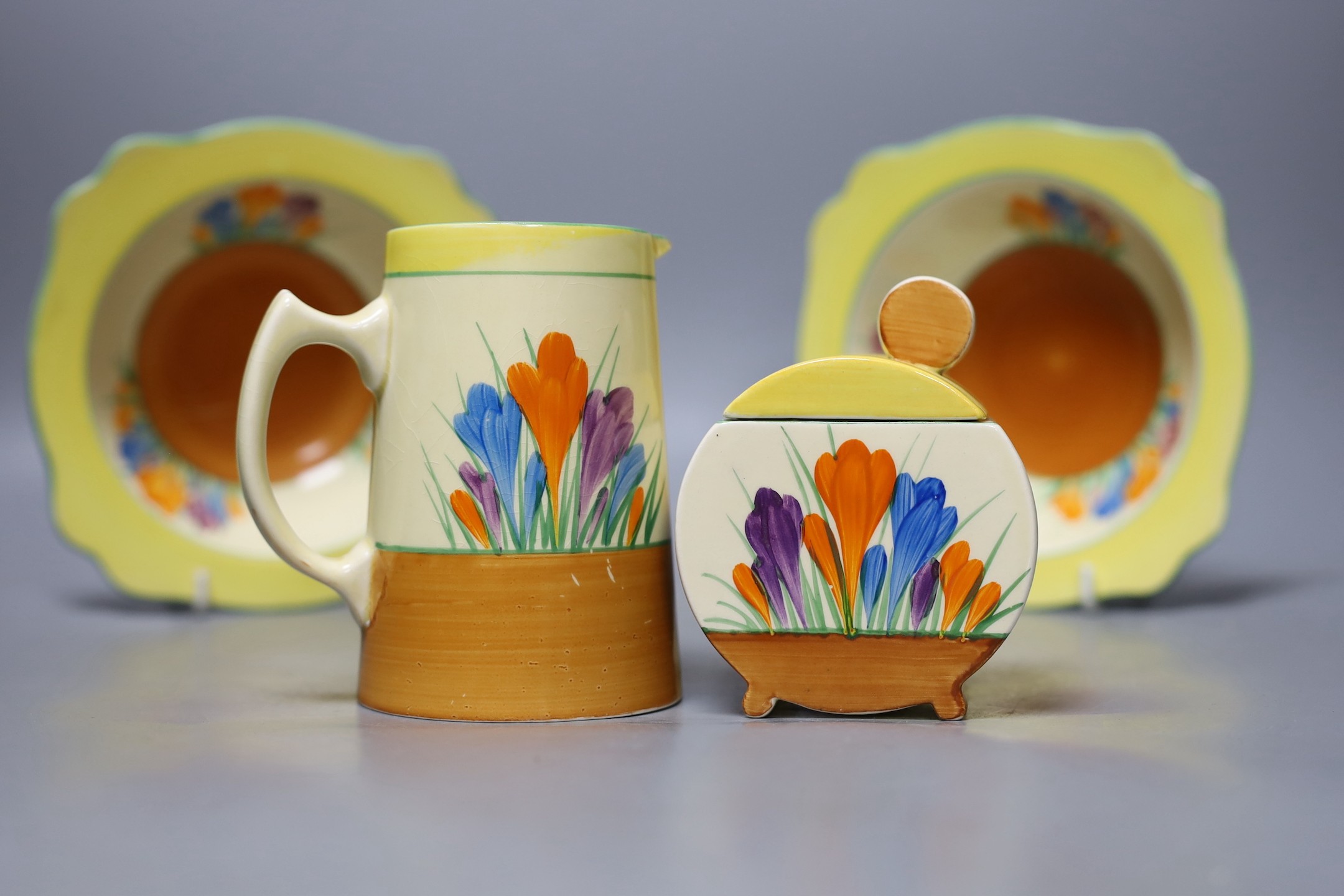 A Clarice Cliff crocus jug, 2 dishes and a jam pot and cover